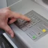 Muž zadává PIN u bankomatu