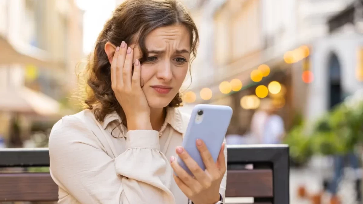 Žena nervózně kouká do telefonu