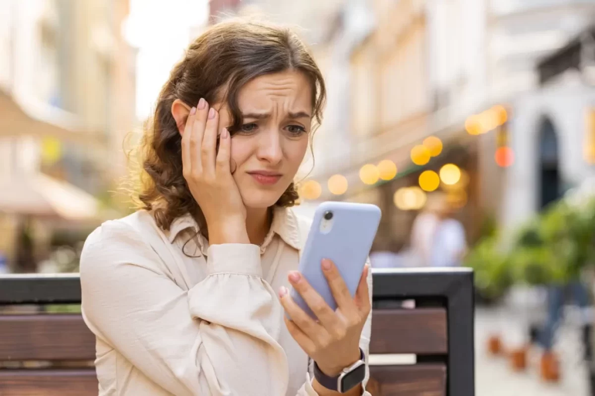 Žena nervózně kouká do telefonu