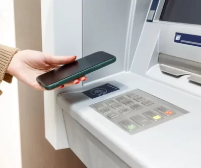 Žena přikládá telefon k bankomatu
