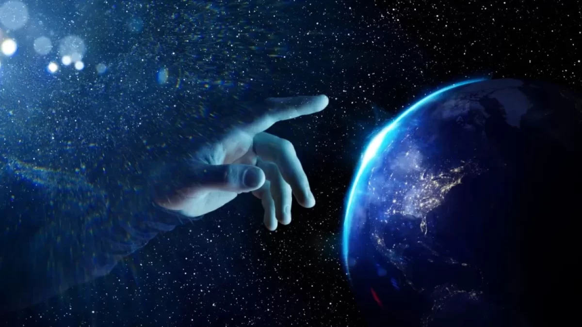 Vesmírná scéna ukazuje ruku, která se natahuje směrem k planetě Zemi, jako by ji právě dotvářela nebo uváděla do pohybu.