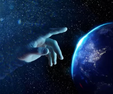 Vesmírná scéna ukazuje ruku, která se natahuje směrem k planetě Zemi, jako by ji právě dotvářela nebo uváděla do pohybu.