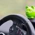 Interiér auta s detailem na volant a malou zelenou pokladničku ve tvaru prasátka, která stojí na palubní desce.