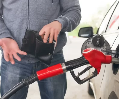 Muž u benzínové stanice tankuje a dívá se do prázdné peněženky