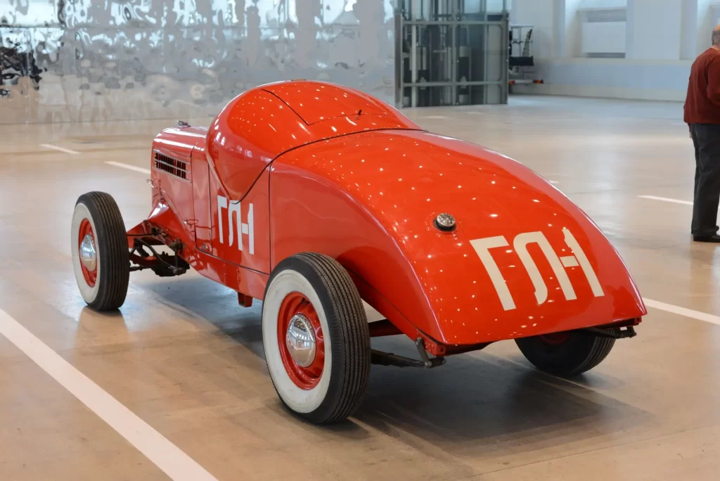 gaz2 - Techsvět Replika sovětského závodního vozu GAZ GL-1 v zářivě červené barvě vystavená v moderním muzeu.