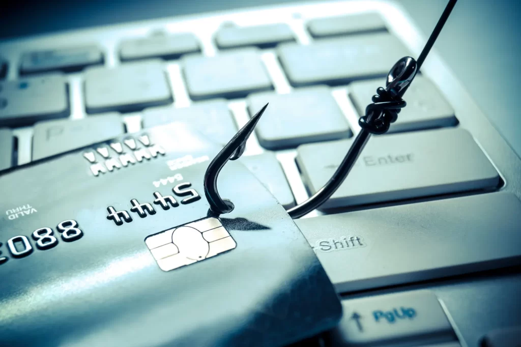 hacker2 - Techsvět Detailní záběr na bankovní kartu zavěšenou na rybářském háčku, položenou na klávesnici počítače.