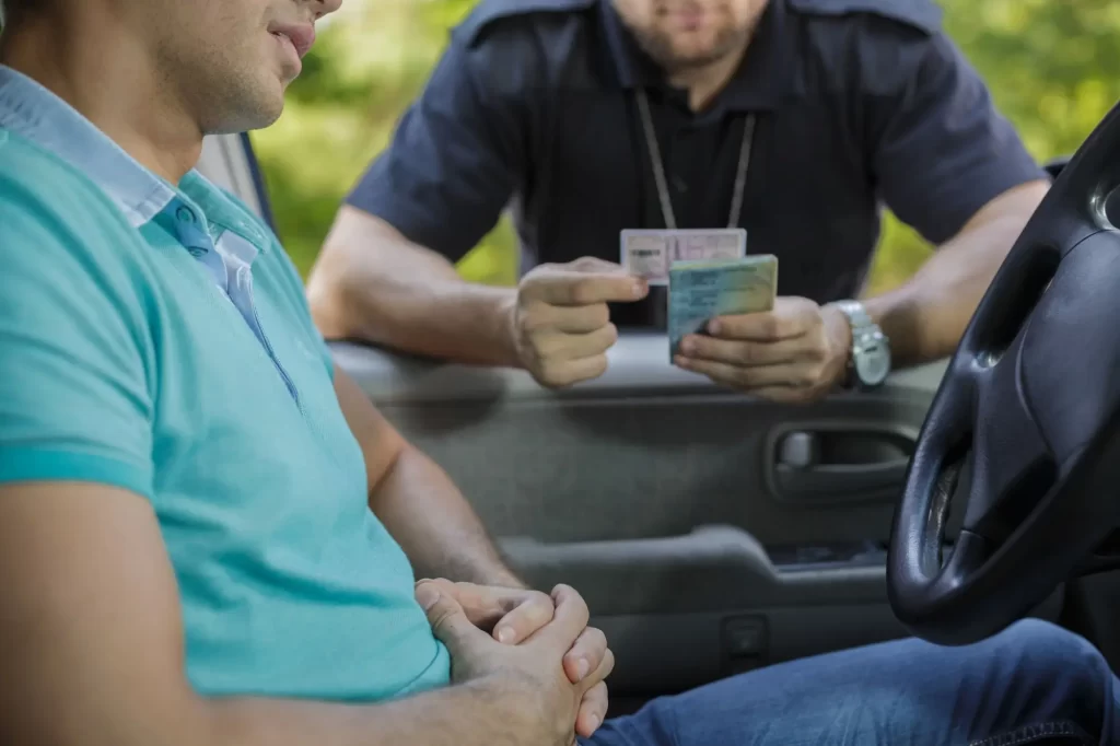 Doživotní řidičský průkaz končí: Od nynějška si ho budete muset po 10 letech udělat znovu - Techsvět Policista stojí u otevřeného okénka auta a kontroluje doklady řidiče, konkrétně řidičský průkaz.