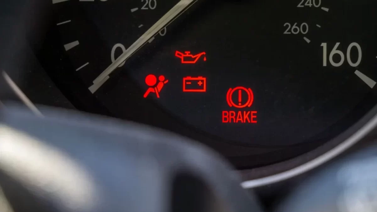 Detail palubní desky automobilu s několika rozsvícenými výstražnými kontrolkami.