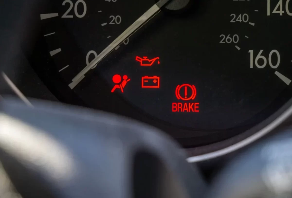 Detail palubní desky automobilu s několika rozsvícenými výstražnými kontrolkami.