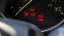 Detail palubní desky automobilu s několika rozsvícenými výstražnými kontrolkami.
