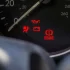 Detail palubní desky automobilu s několika rozsvícenými výstražnými kontrolkami.