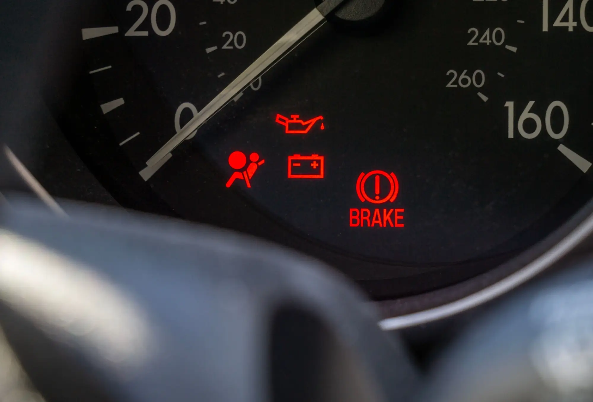 Detail palubní desky automobilu s několika rozsvícenými výstražnými kontrolkami.