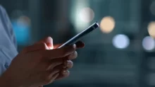 Detail rukou držících chytrý telefon.