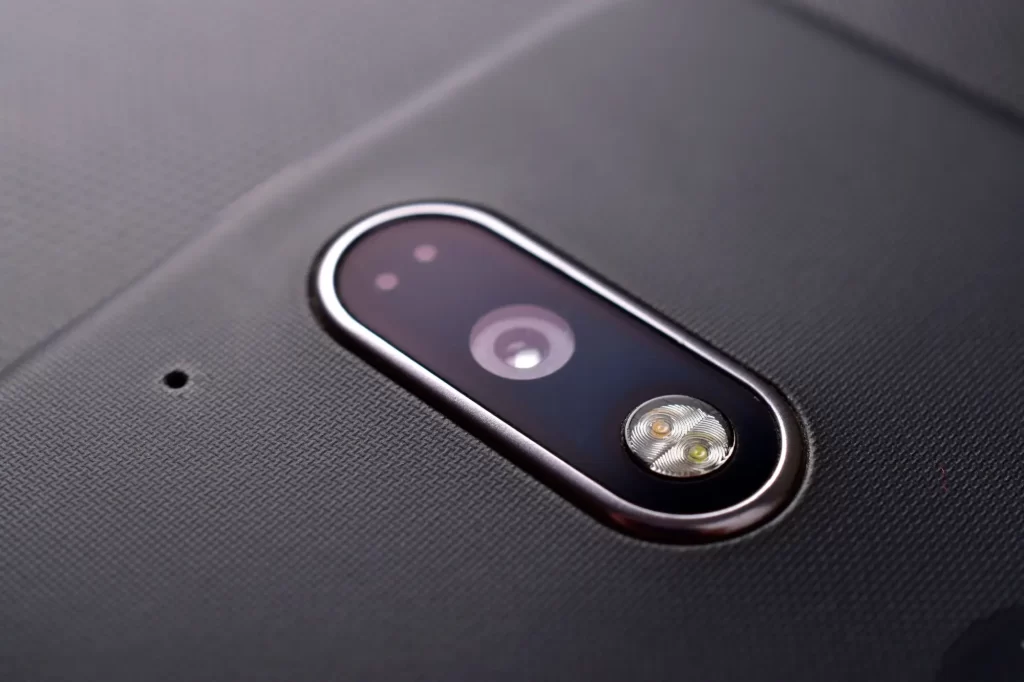 mobil3 - Techsvět Detailní záběr na zadní stranu mobilního telefonu ukazuje čočku fotoaparátu, blesk a vedle nich malý kulatý otvor – sekundární mikrofon.