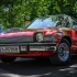 Červený AMC Pacer, zaparkovaný venku pod stromem