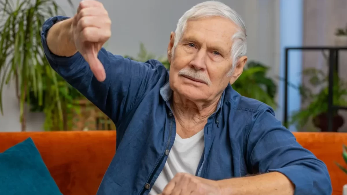 Senior v modré košili ukazuje palec dolů