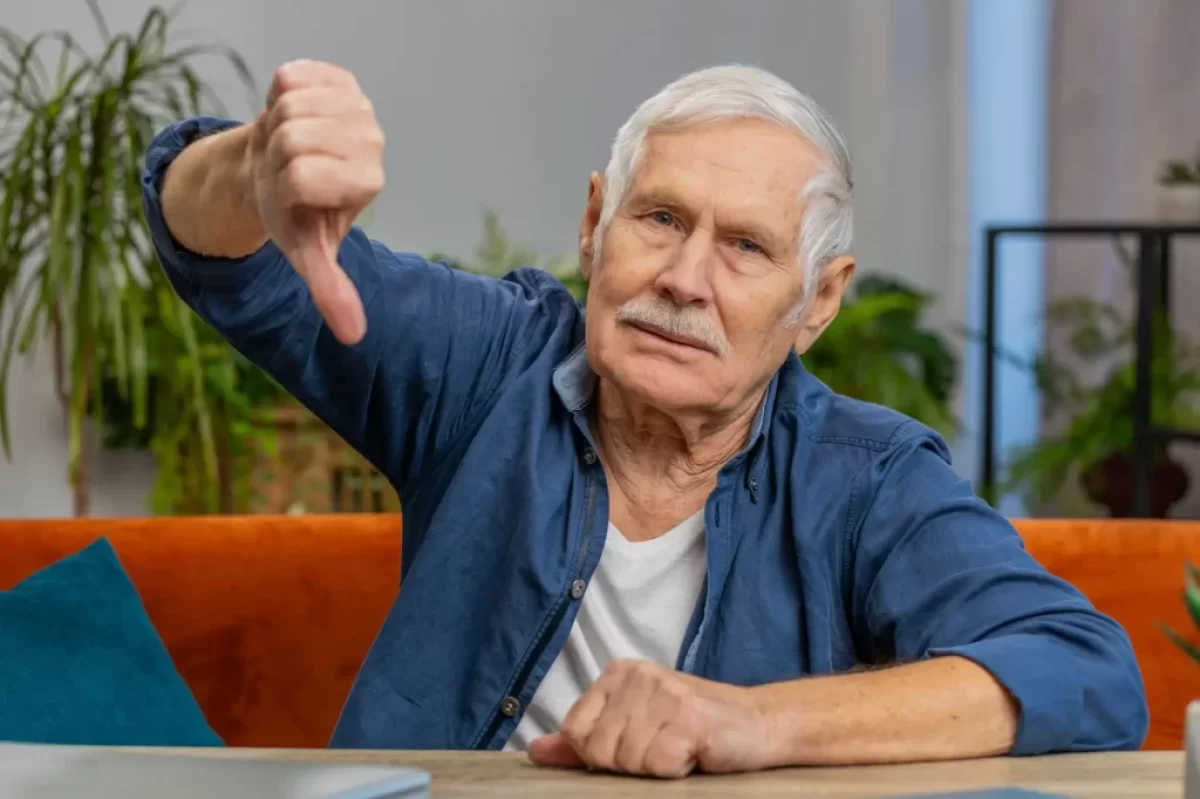 Senior v modré košili ukazuje palec dolů