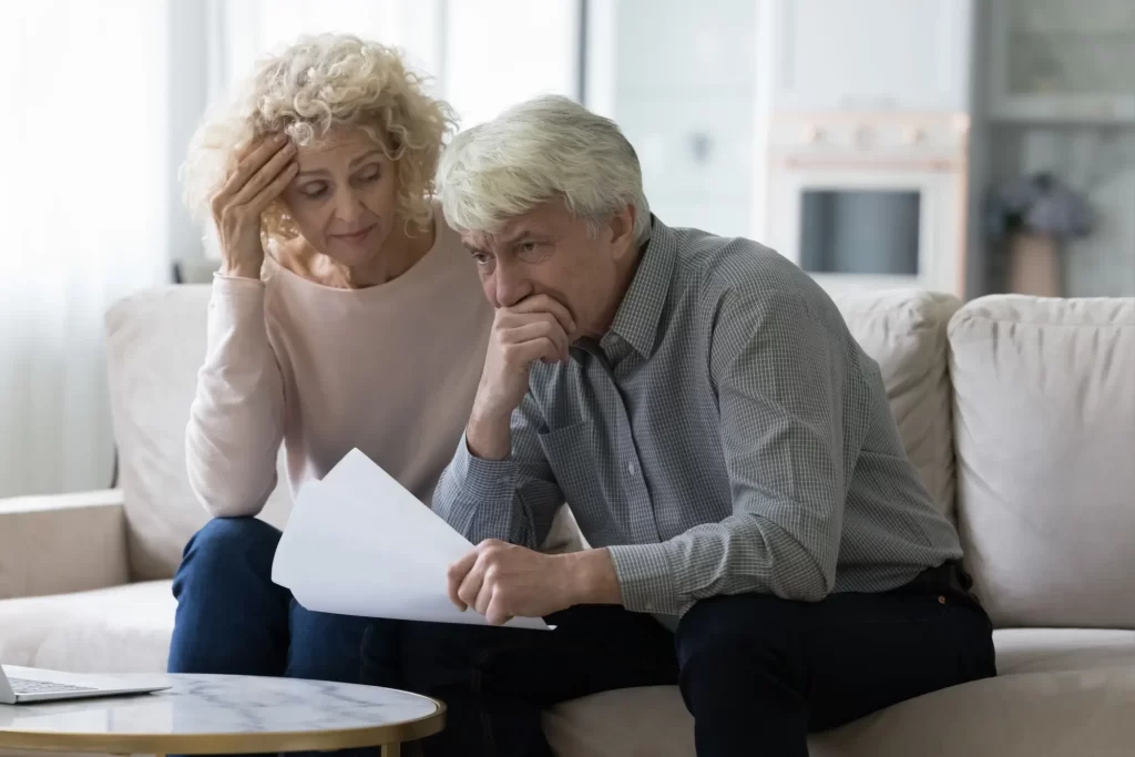 Dvopjice seniorů ustaraně čte dokumenty