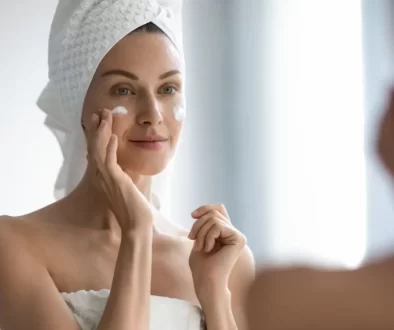 žena před zrcadlem aplikuje krém na tvář