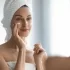 žena před zrcadlem aplikuje krém na tvář
