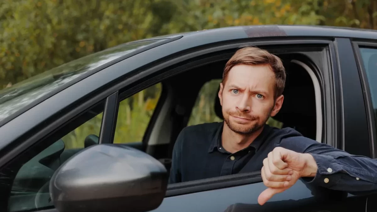 muž v autě s palcem dolů