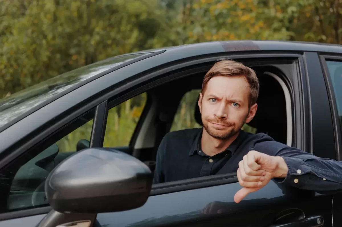 muž v autě s palcem dolů
