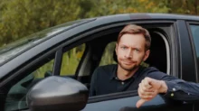 muž v autě s palcem dolů