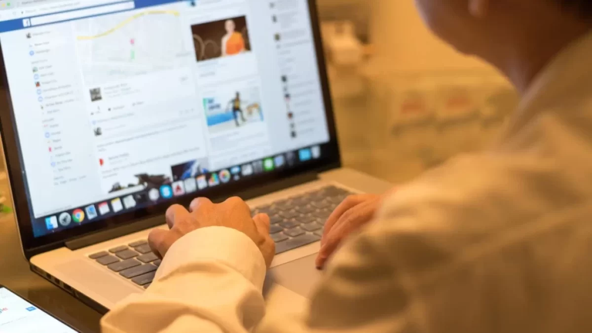 muž u notebooku, na kterém má Facebook