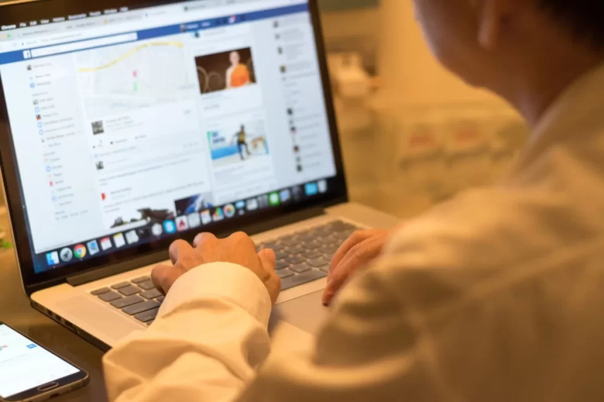 muž u notebooku, na kterém má Facebook