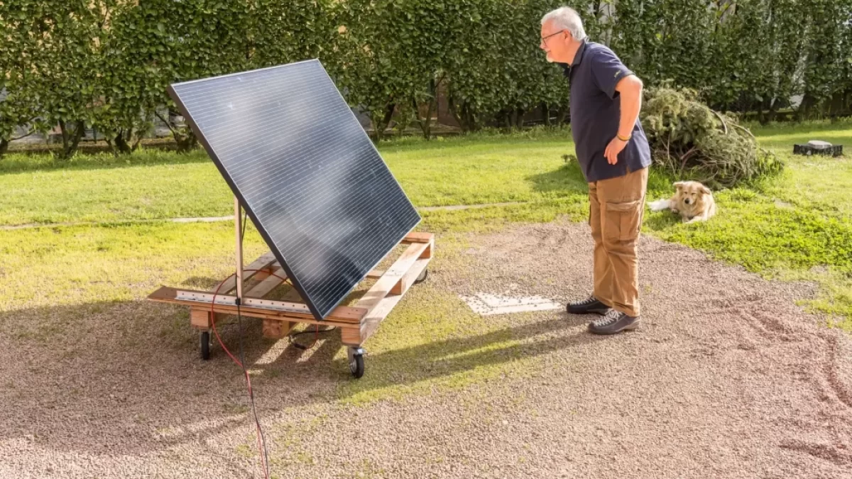 Starší muž v černém tričku se dívá na zahradě na fotovoltaický panel