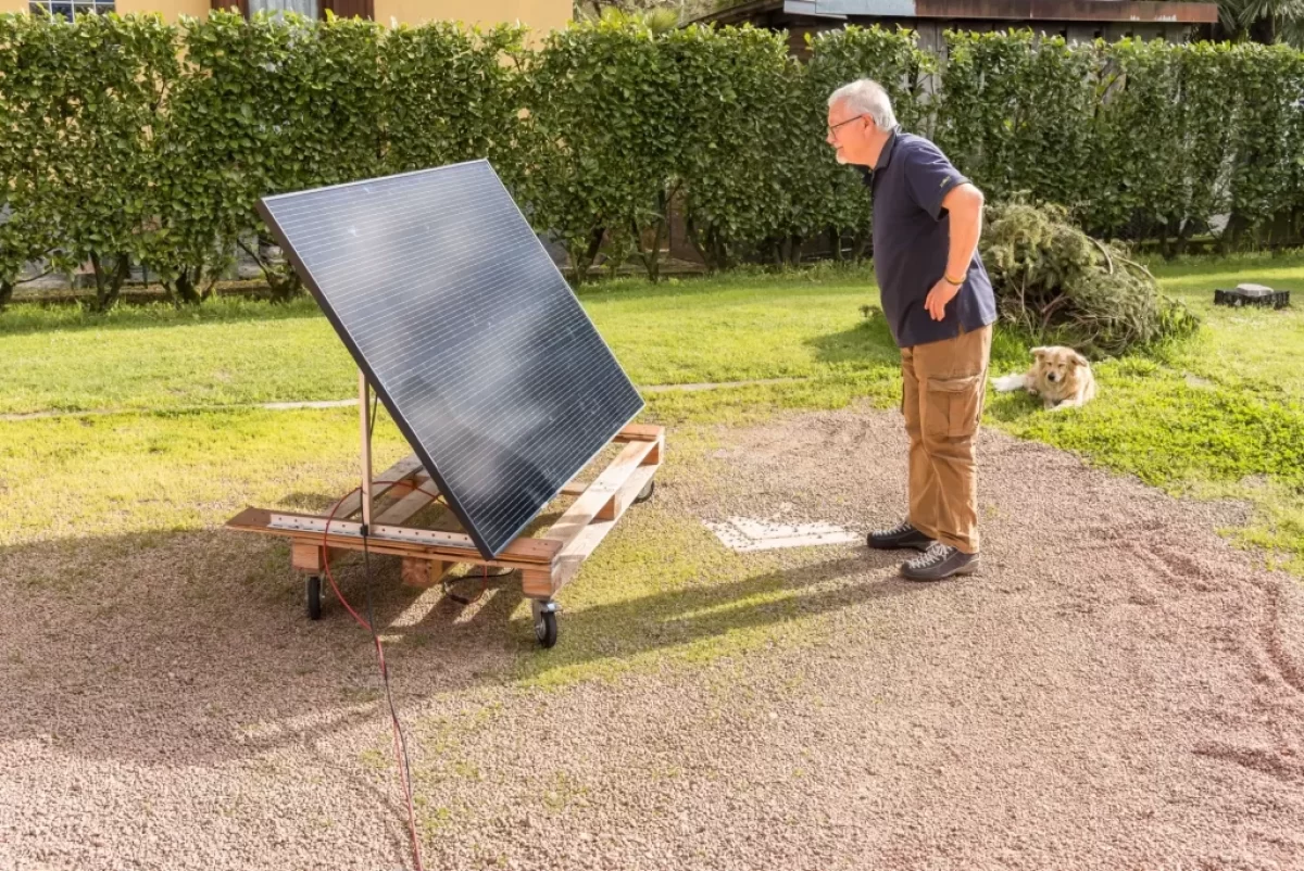 Starší muž v černém tričku se dívá na zahradě na fotovoltaický panel