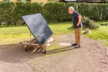 Starší muž v černém tričku se dívá na zahradě na fotovoltaický panel