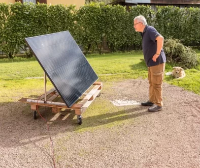 Starší muž v černém tričku se dívá na zahradě na fotovoltaický panel