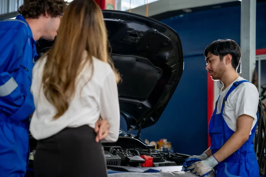 stk2 1 - Techsvět Dva automechanici a jedna žena u otevřené kapoty vozu.