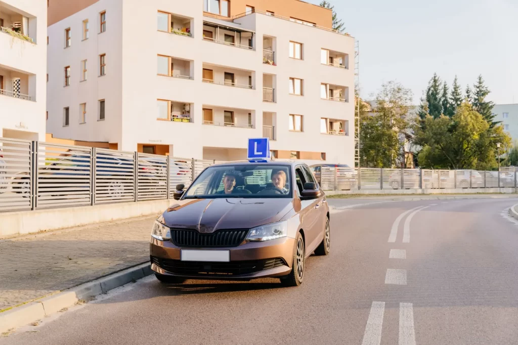 test3 - Techsvět Auto autoškoly s modrým označením „L“ na střeše projíždí městskou ulicí