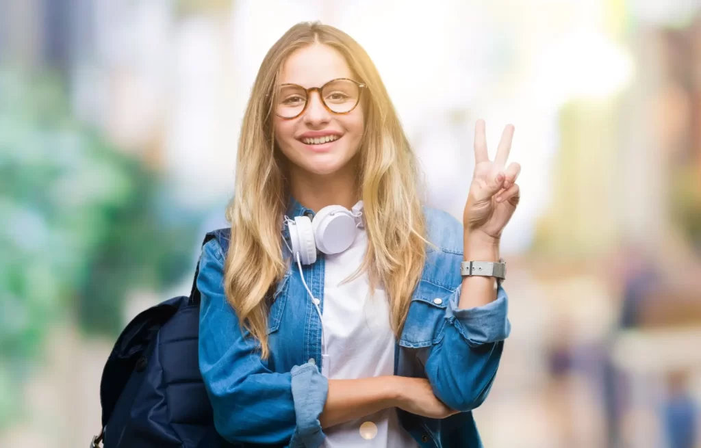 vic3 - Techsvět MLadá blond dívka v modré košili ukazuje prsty symbol vítězství