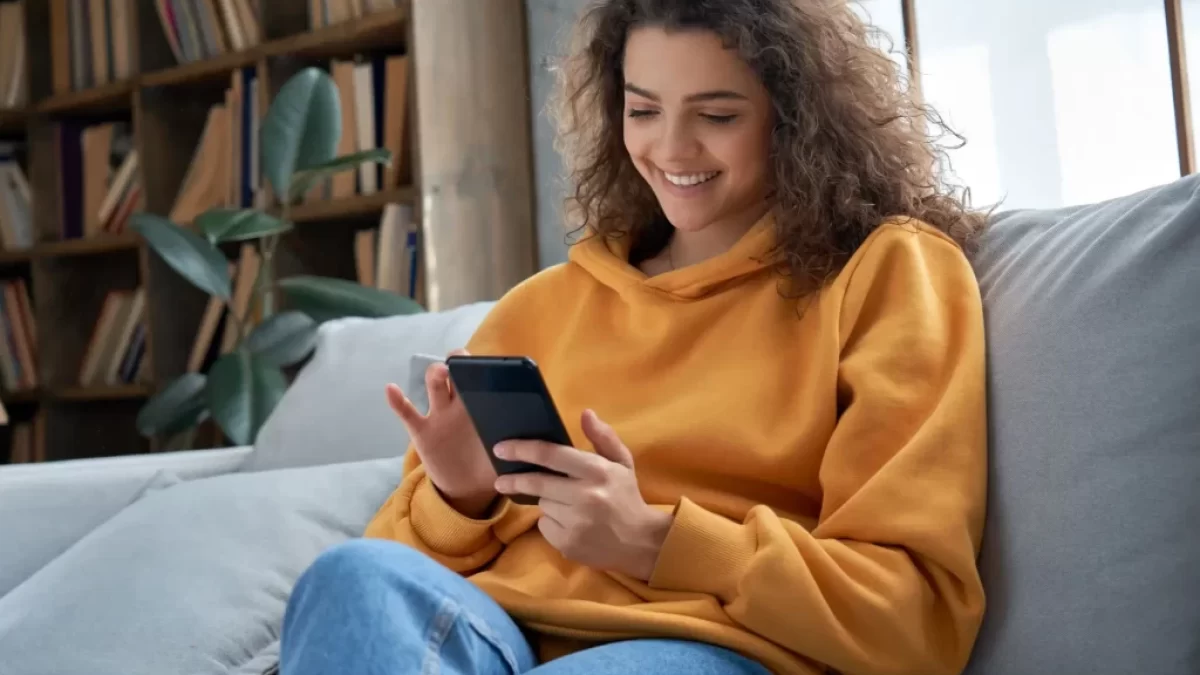 Usmívající se mladá žena s mobilním telefonem