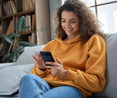 Usmívající se mladá žena s mobilním telefonem