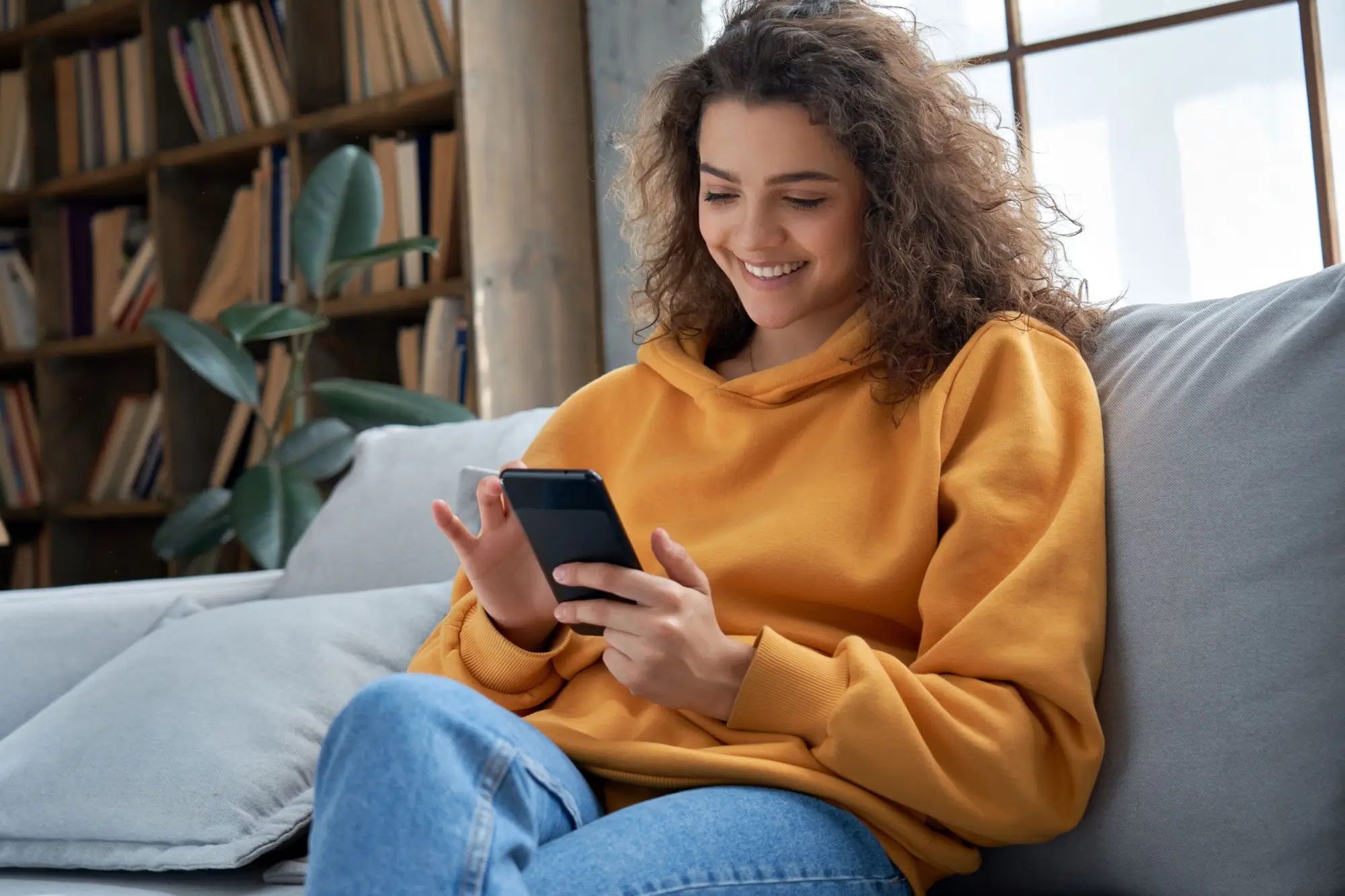 Usmívající se mladá žena s mobilním telefonem