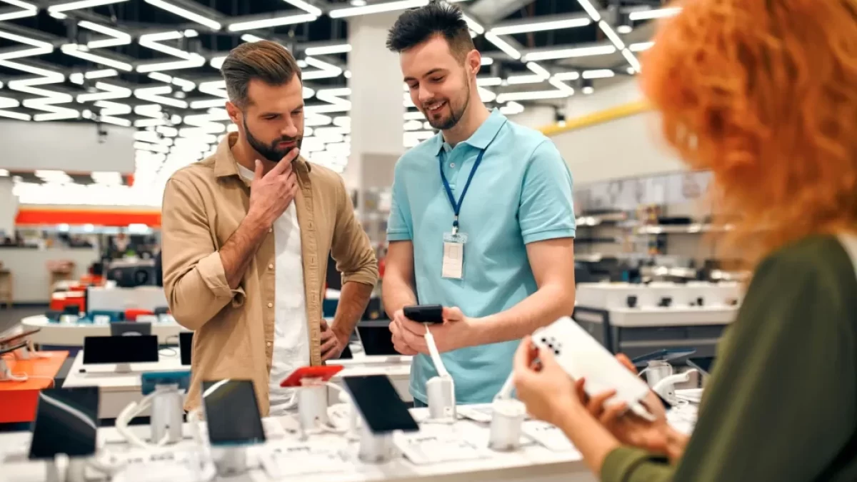 Prodavač radí muži, který si vybírá nový smartphone v obchodě
