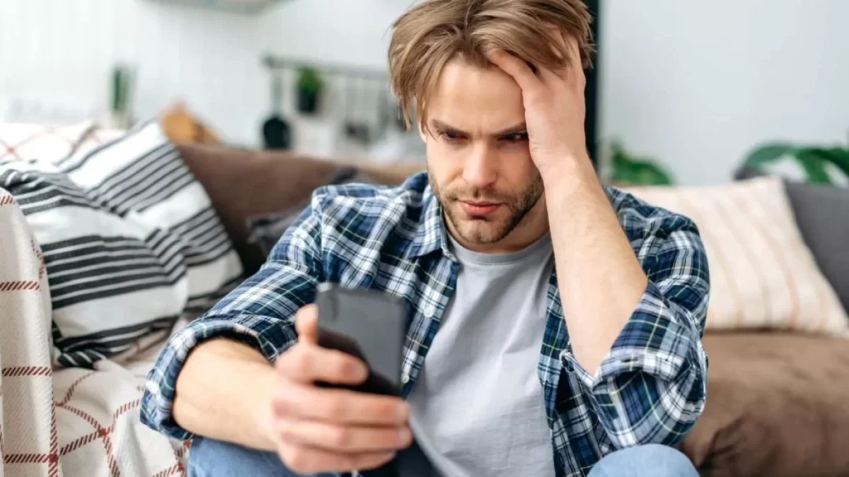muž smutně kouká do mobilu