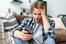 muž smutně kouká do mobilu