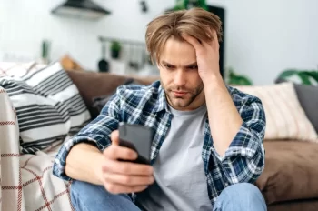 muž smutně kouká do mobilu