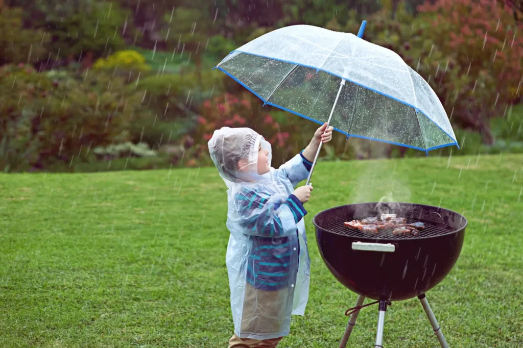 Shutterstock_2300500629 - Techsvět Kluk griluje v dešti s deštníkem