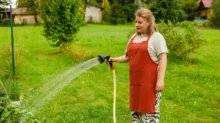 paní zalévá hadicí zahradu