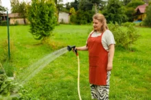 paní zalévá hadicí zahradu