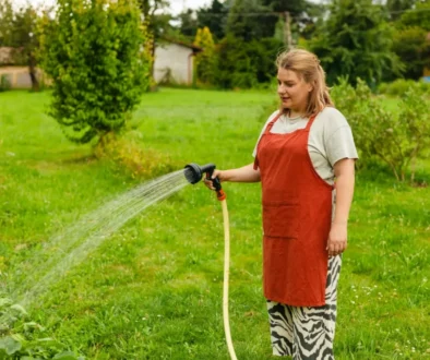 paní zalévá hadicí zahradu