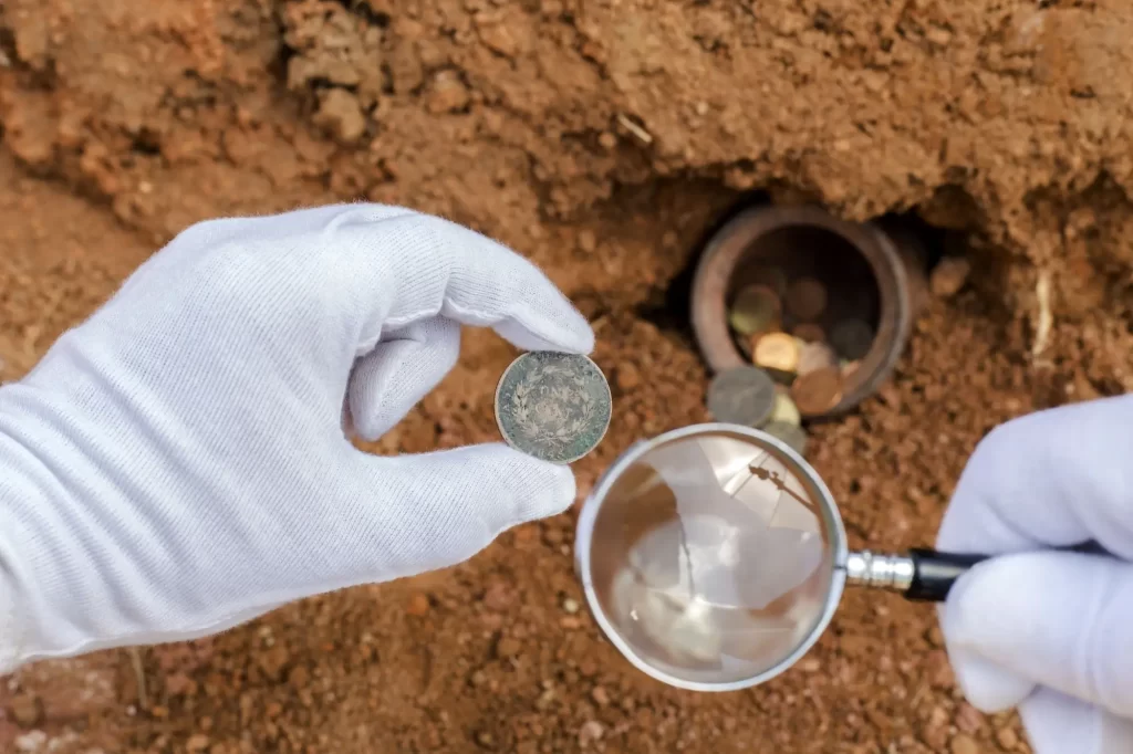 V hrnci vědci našli 2800 středověkých mincí - Techsvět Archeolog zkoumá staré mince