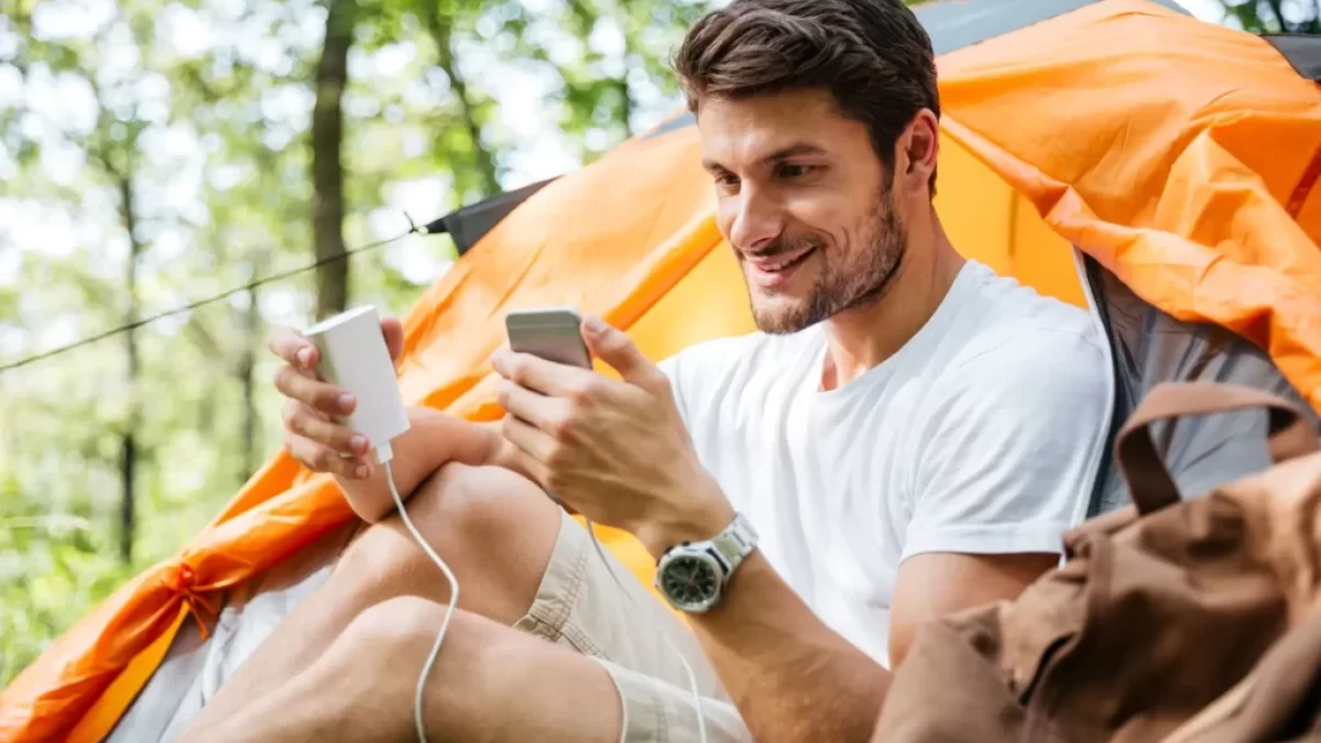 muž nabíjí telefon u stanu