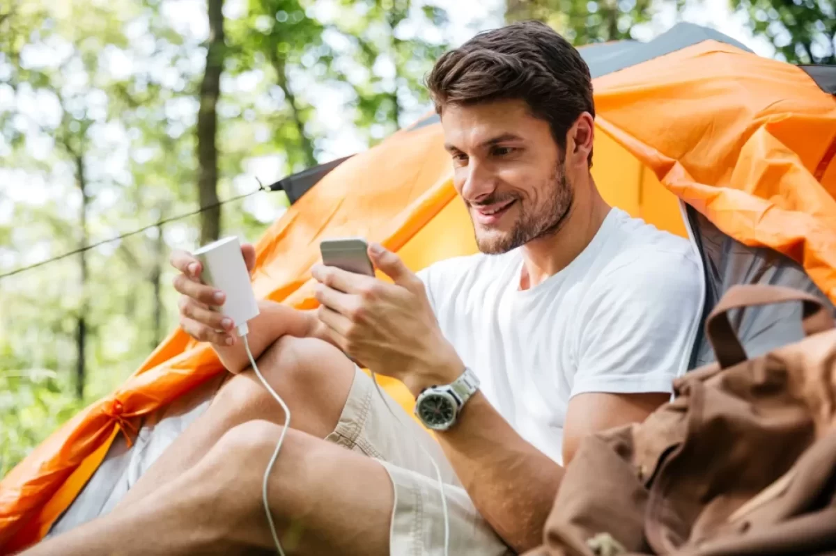 muž nabíjí telefon u stanu